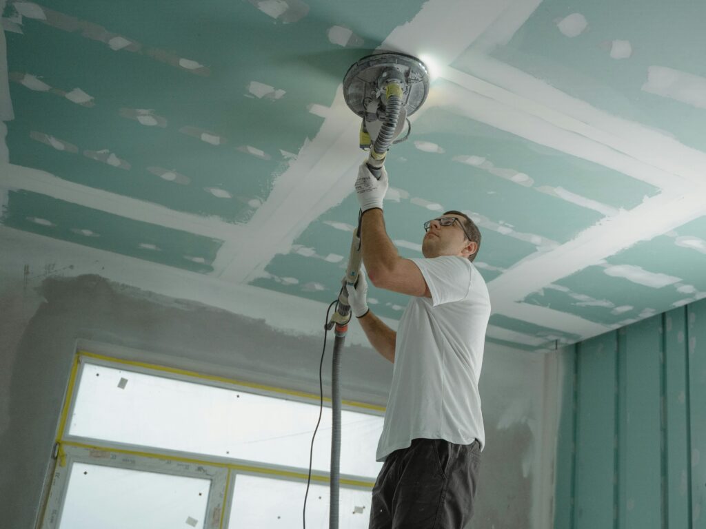 pexels-photo-6474343-6474343 A professional worker sanding the ceiling during a home renovation project. Indoor construction setting.